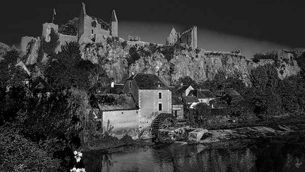 A darkened village with a castle standing above it.